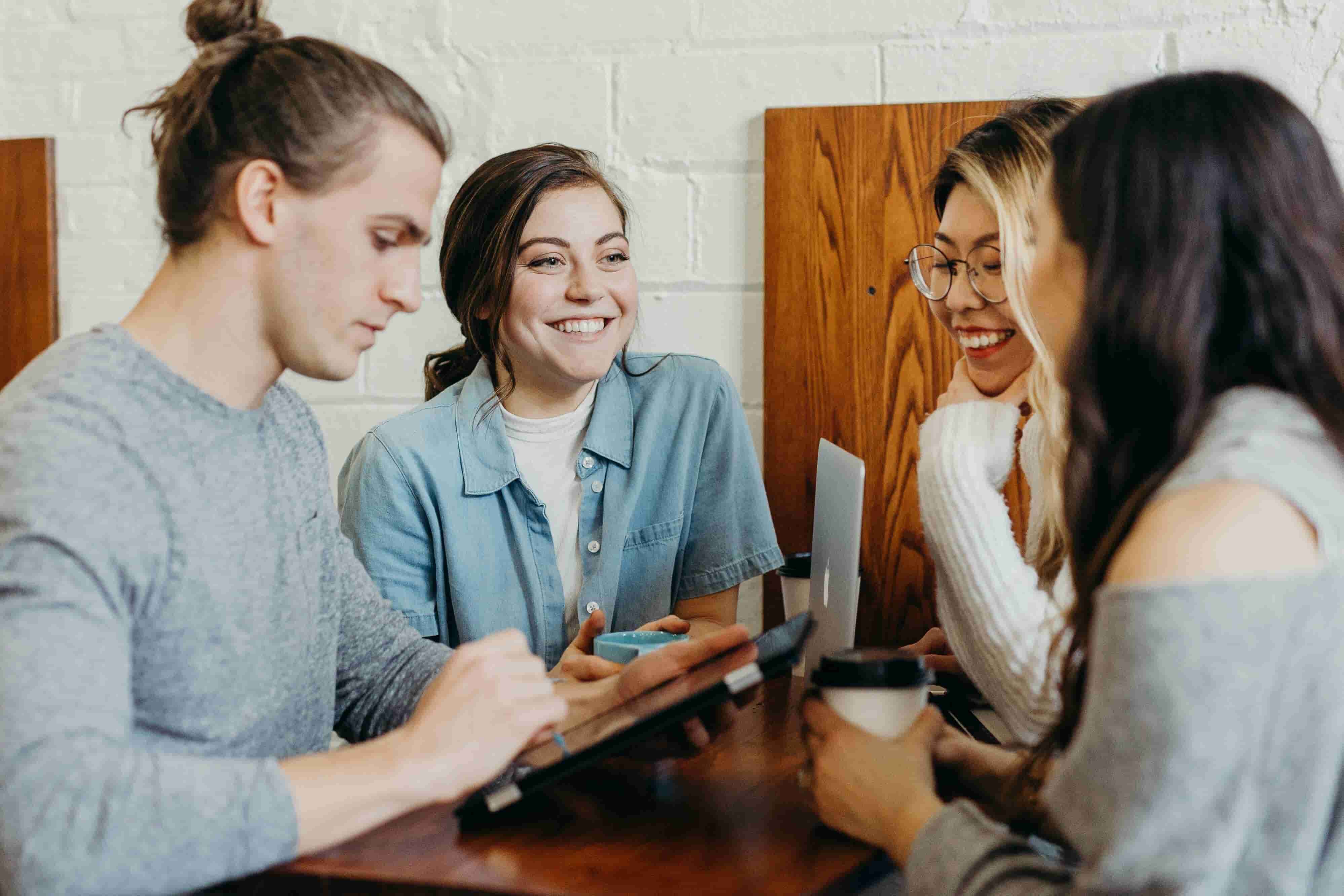 group of young business professionals chatting over coffee with tablets in hand